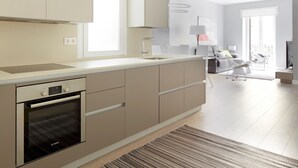 A modern kitchen with integrated appliances, a dining area with a sofa and chairs, and a balcony with a railing. - Zabaleta Beach by FeelFree Rentals (Donostia)