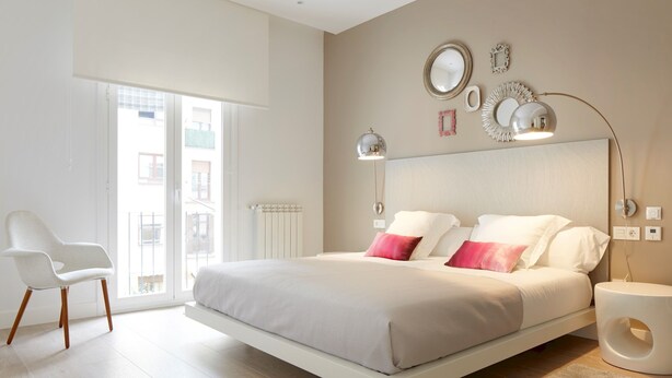 A modern bedroom with a large bed, a white chair, and a view of the outside. - Zabaleta Beach by FeelFree Rentals (Donostia)