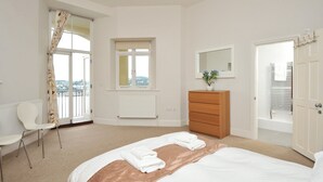 Une chambre à coucher avec un lit, une chaise, une commode, une fenêtre et une porte.