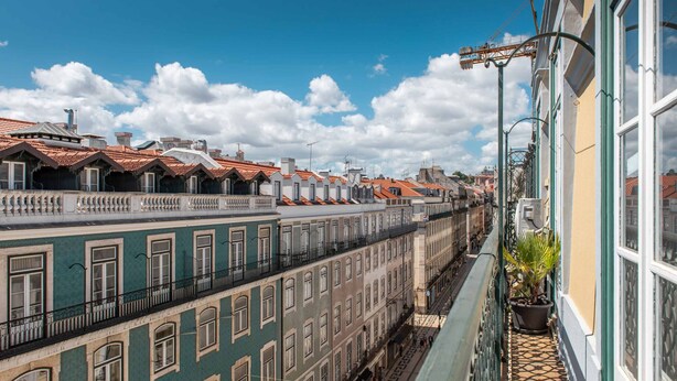 Une rangée de bâtiments historiques aux toits recouverts de tuiles rouges, dotés de balcons et bordée d’une étroite ruelle.