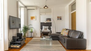 Un salon avec un canapé, une table basse, un téléviseur et une plante.