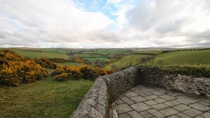 A stone bench overlooking a valley with fields and a stone wall. - The School House, Countisbury (Lynton)