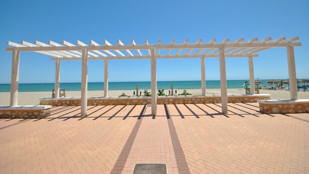 Eine Pergola am Strand mit freiem Blick auf den Ozean.