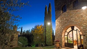 A stone building with an arched entrance, a well-maintained lawn, and a tall tree in the background. - Historic Stone House Casanova (Cinigiano)