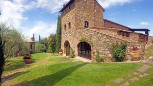 A stone building with a courtyard, a small tower, and a staircase leading to the entrance. - Historic Stone House Casanova (Cinigiano)