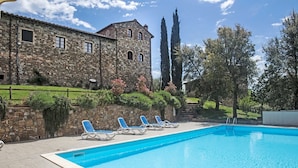 A stone building with a swimming pool, lounge chairs, and a garden. - Historic Stone House Casanova (Cinigiano)