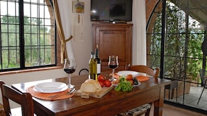 A dining table with plates, glasses, bread, tomatoes, and a bottle of wine.