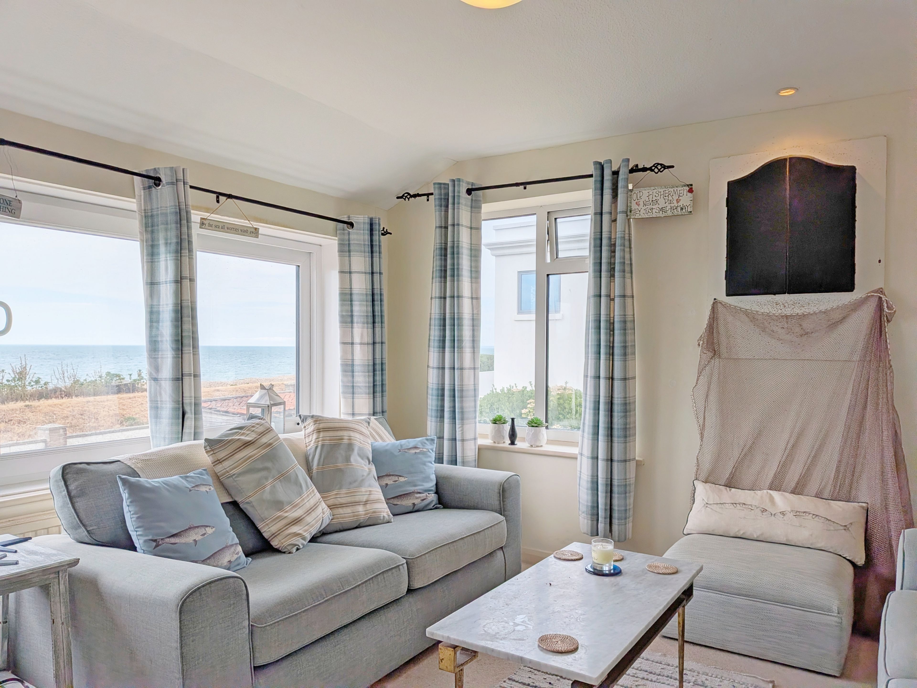 Una habitació amb un sofà gris, una taula petita i vista al mar.