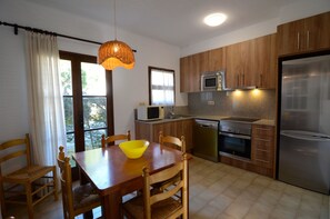 A compact kitchen with wooden cabinets, a stainless steel refrigerator, a microwave, and a dishwasher.
