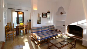Ein Wohnzimmer mit einer Couch, einem Esstisch, Stühlen und einem Kamin.