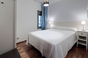 A bedroom with a bed, bedside tables, a window with curtains, and a hanging light fixture. - Bright Eixample Flat Alibei 1 Natural Light & AC (Barcelona)