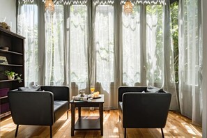A room with two black chairs, a small table with breakfast items, and sheer curtains. - Bright Eixample Flat Alibei 1 Natural Light & AC (Barcelona)