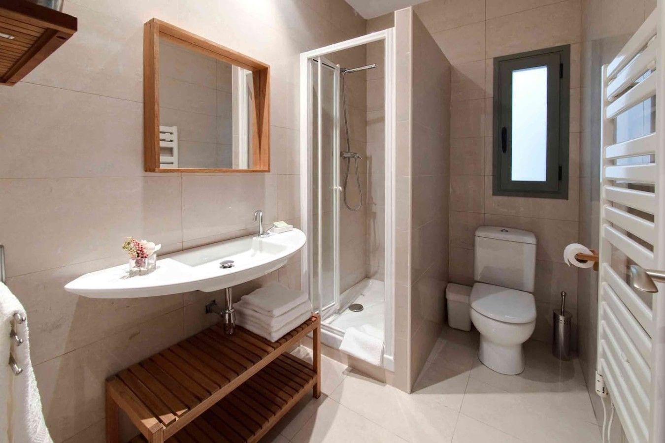 A bathroom with a sink, shower, toilet, and a window.