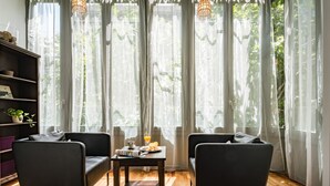 A modern living room with two dark sofas, a wooden coffee table with breakfast items, and sheer curtains allowing natural light. - Alibei 1 - Habitat Apartments (Barcelona)