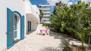 A courtyard with a white building, blue shutters, and a table with chairs.