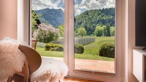 Quarto com porta de vidro deslizante que dá para uma varanda com vista para as montanhas.