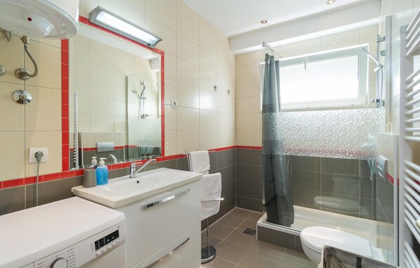 A modern bathroom with a white sink, mirror, and shower area. - Lovely home in Zrnovnica (Zrnovnica)