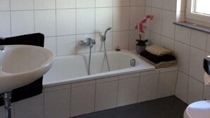 Un baño con bañera, lavamanos e inodoro.