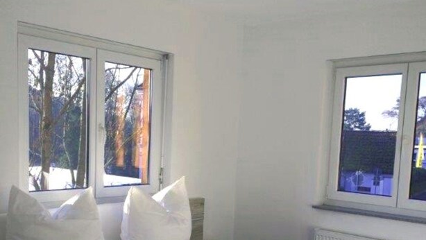 Un dormitorio con una cama, dos ventanas y un radiador.