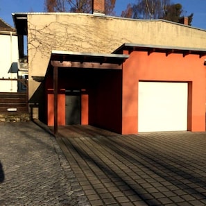 Un bâtiment doté d’une porte de garage, d’une allée pavée et d’un chemin en briques menant à l’entrée.