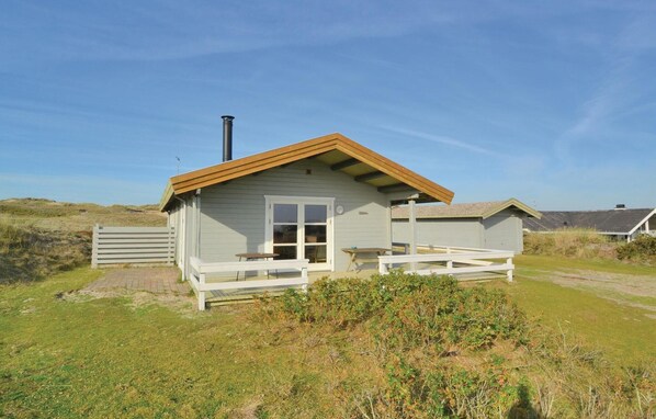 A small, single-story cabin with a wooden deck and a chimney. - Nice home in Fanø with house sea view (Fanø)