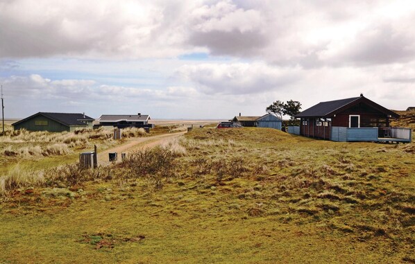 A rural landscape with several buildings, including a large house with a blue exterior and a smaller structure with a green roof. - Nice home in Fanø with house sea view (Fanø)