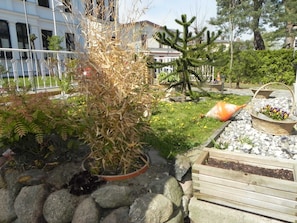 Un jardin où l’on trouve une variété de plantes, un banc en bois et une clôture en métal.