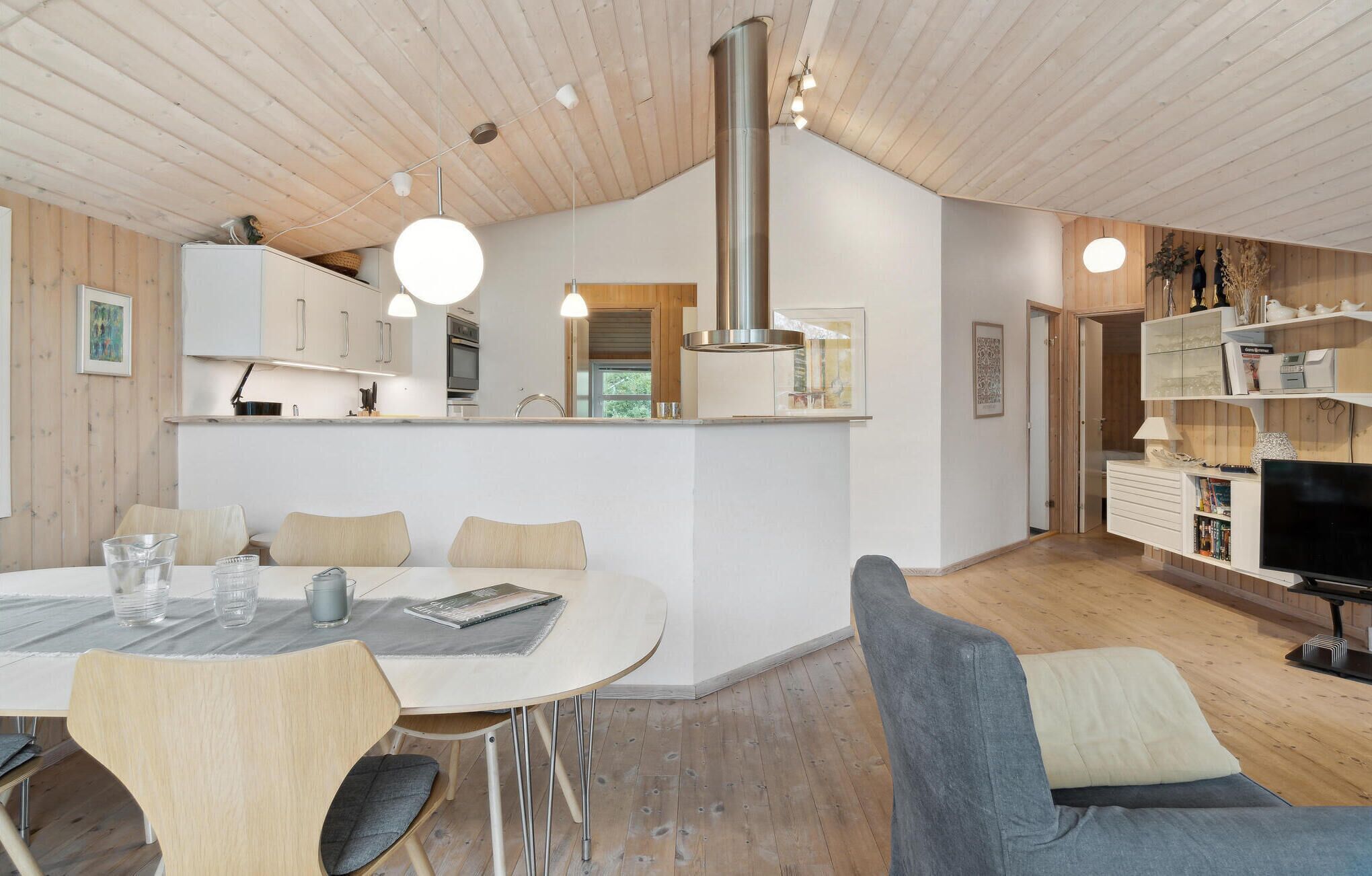 Une cuisine moderne avec des meubles en bois, un îlot central et des luminaires suspendus.