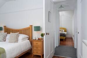A bedroom with a wooden headboard, a bedside table with a lamp, and a nightstand with a plant.
