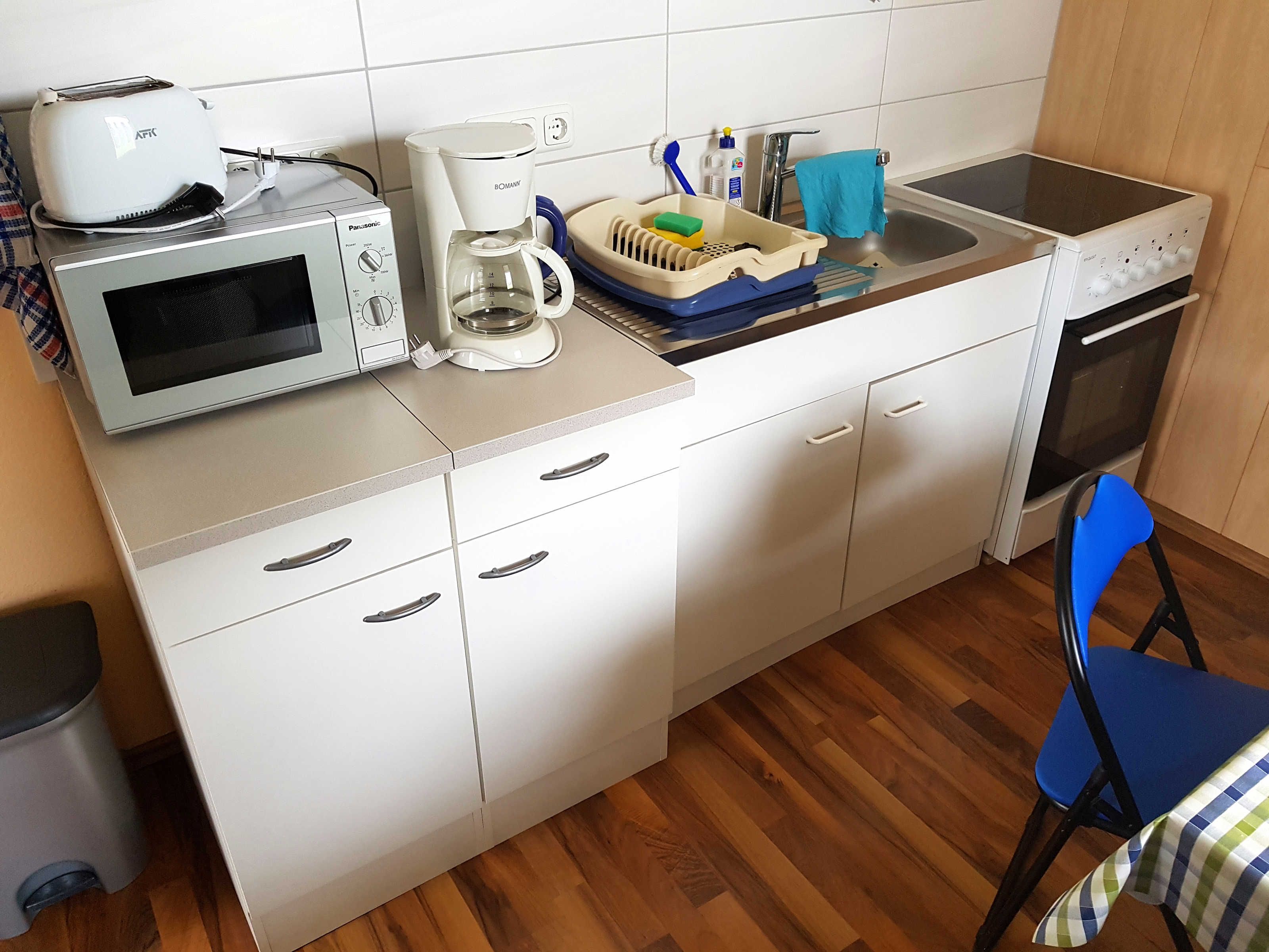 Une petite cuisine équipée d’un four à micro-ondes, d’un grille-pain, d’une machine à café, d’un évier et d’un four.