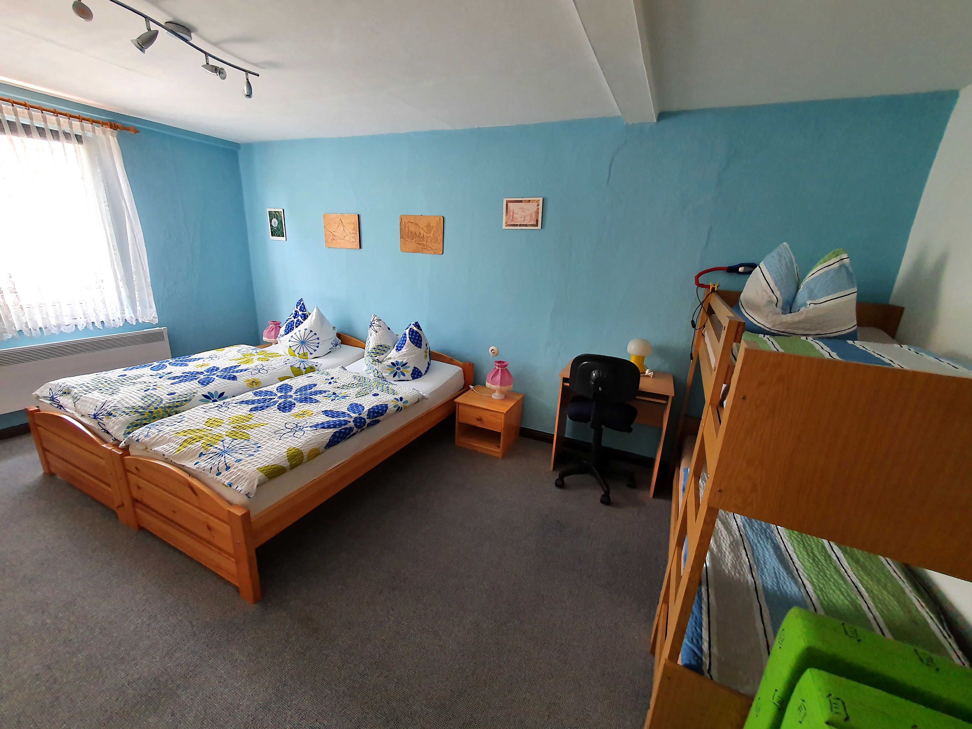 A bedroom with a double bed, a desk, a chair, and a bunk bed.