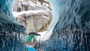 Un túnel de hielo con una vista despejada de una formación rocosa cubierta de nieve al final.