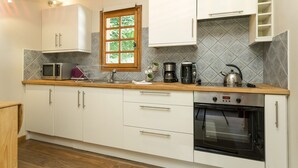 Una cocina moderna con armarios blancos, horno empotrado, cafetera y microondas.