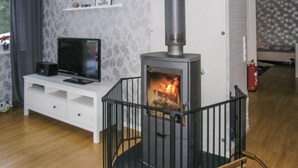 Un salon avec une cheminée, un téléviseur posé sur un meuble blanc et un mur orné d’une citation inspirante.