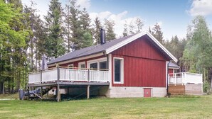 Une cabane rouge dotée d’un balcon, d’une cheminée et d’une petite terrasse.