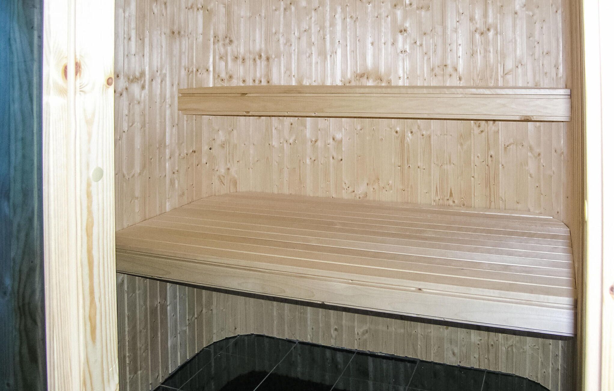 A sauna with a wooden bench and a tiled floor.