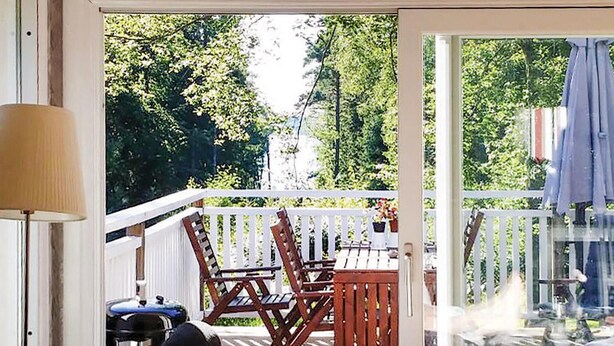 Une terrasse en bois avec une table et des chaises, une lampe et un barbecue.