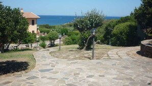 Un chemin de pierres menant à un bâtiment d’où l’on a vue sur la mer.