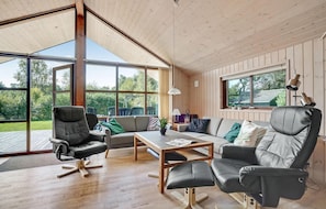 A spacious living area with a wooden ceiling, large windows, a sofa set, a coffee table, and a dining table. - Beautiful home in Ansager with sauna (Ansager)