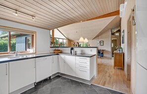 A modern kitchen with a large island, wooden ceiling, and large windows. - Beautiful home in Ansager with sauna (Ansager)