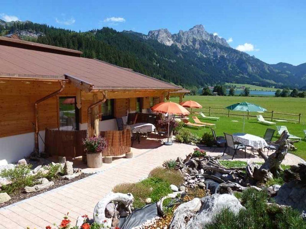 A wooden building with outdoor seating and a view of mountains.