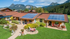 Un bâtiment de style chalet doté de panneaux solaires, d’une terrasse et offrant une vue sur les montagnes.