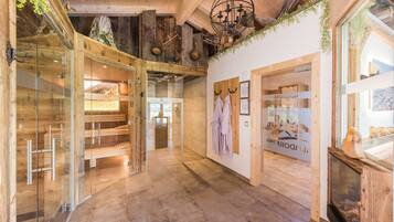 Een modern interieur met een glazen deuropening, houten vloeren en een zichtbare sauna-ruimte.