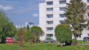 A modern building with multiple windows and balconies, surrounded by green trees and a grassy area. - 2 bedroom cozy apartment in Goslar (Goslar)