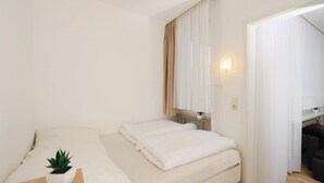 A minimalist bedroom with a bed, a bedside table with a plant, and a window with curtains. - 2 bedroom cozy apartment in Goslar (Goslar)