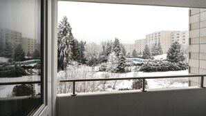 A view from a window with a metal railing, overlooking a snowy landscape with trees and a building in the background. - 2 bedroom cozy apartment in Goslar (Goslar)