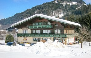 En byggnad i chaletstil med ett sluttande tak, flera balkonger och en bergskedja i bakgrunden.