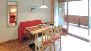 Un comedor con una mesa de madera, sillas tapizadas rojas, una pequeña planta en maceta y una lámpara colgante.