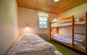 A dormitory room with bunk beds, a window with blinds, a green carpet, and a wall-mounted light fixture. - 2 bedroom amazing home in Grenaa (Grenaa)