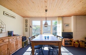A dining area with a wooden table and chairs, a ceiling fan, and a television on a stand. - 2 bedroom amazing home in Grenaa (Grenaa)